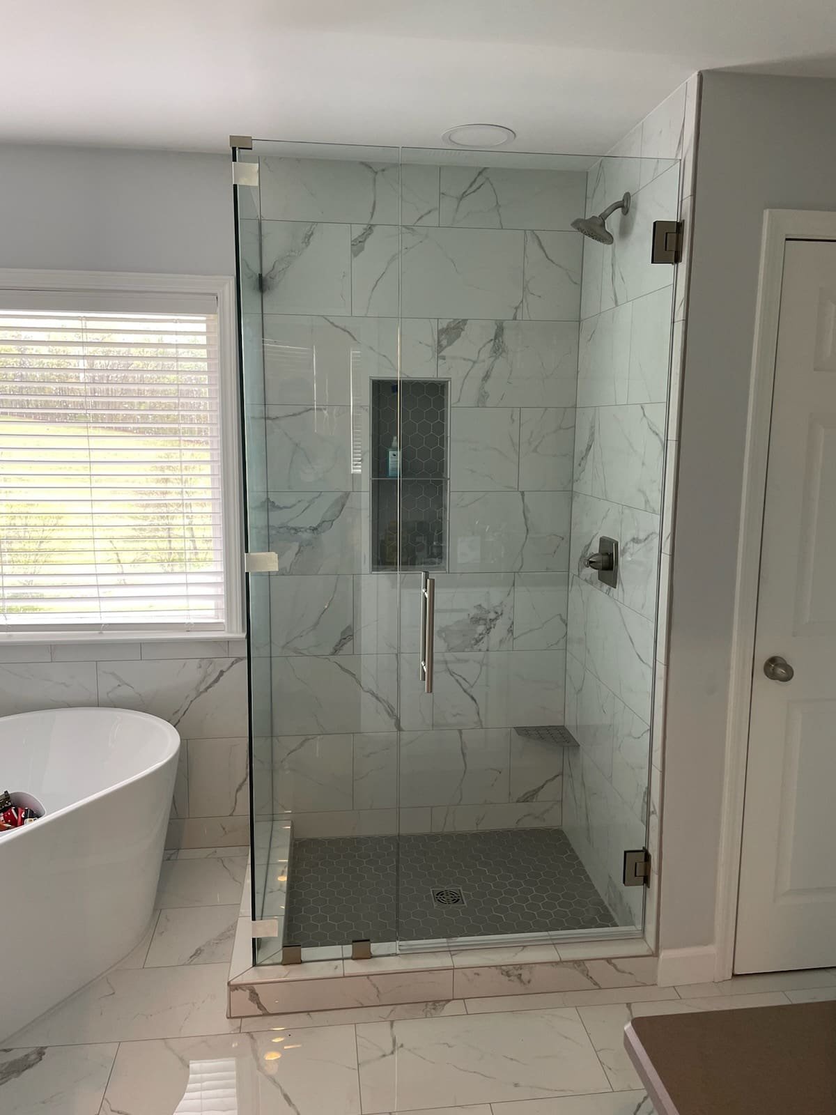 Glass shower beside a freestanding tub