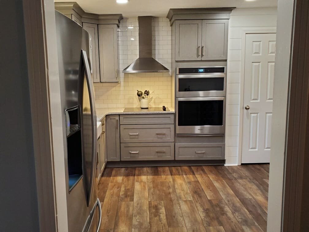 Grey cabinets with wall oven and wood flooring
