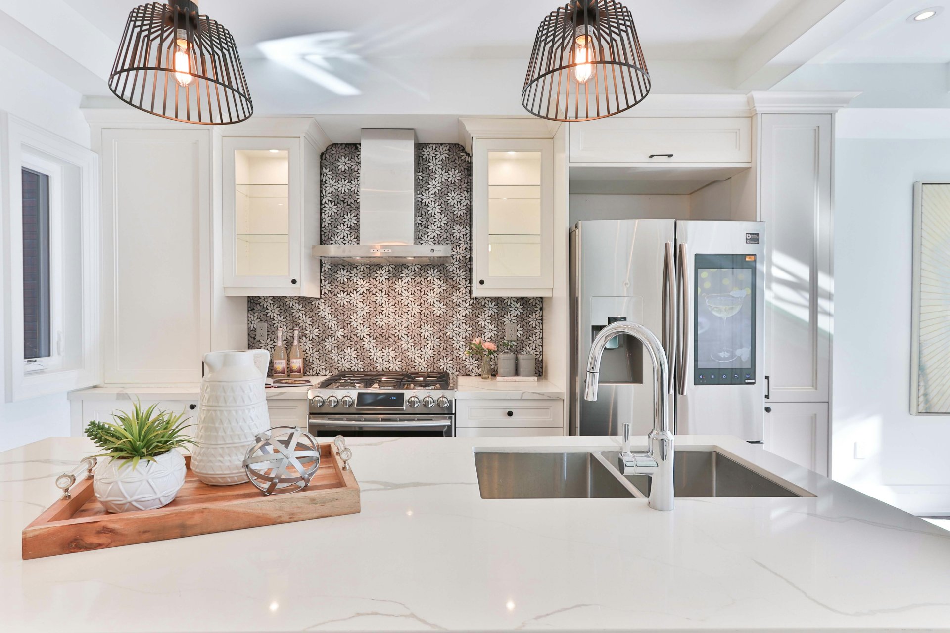 Herringbone tile backsplash beside a stainless sink in a finished kitchen