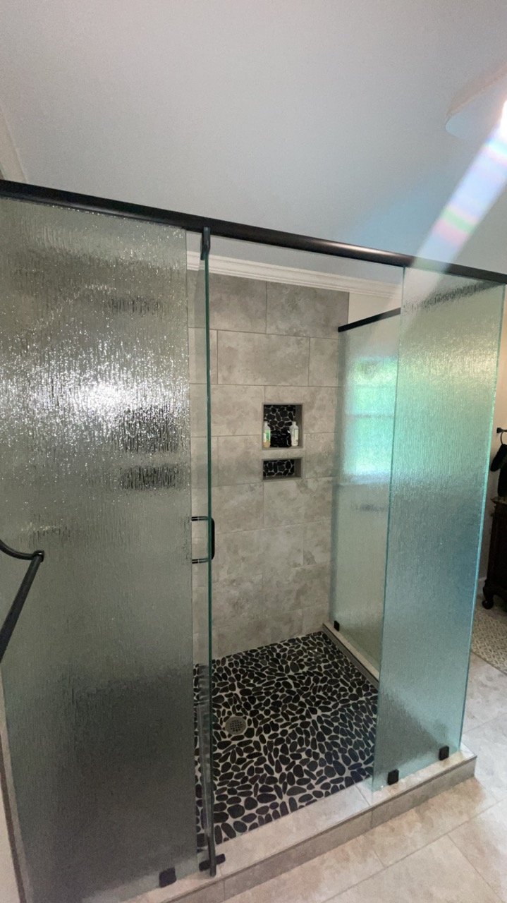 Frameless glass shower with pebble tile floor in a Brentwood bathroom