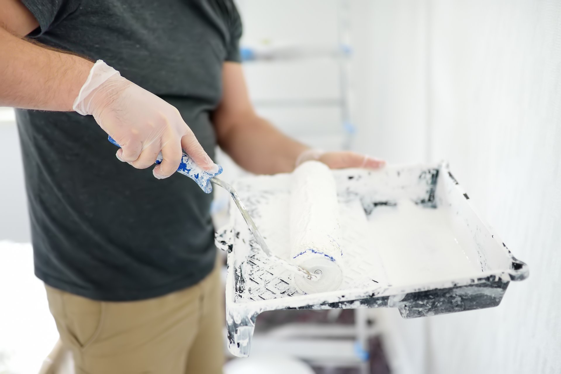 Painter loading a roller with white paint